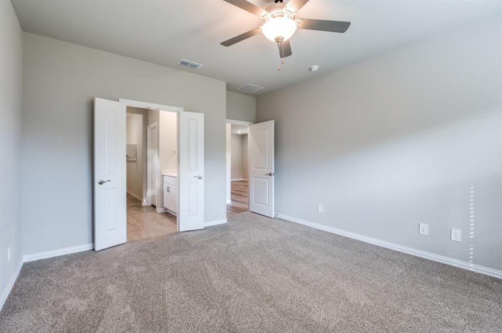 Neutral wall palette with plush carpeting, ceiling fan with integrated lighting, and dual-panel interior doors