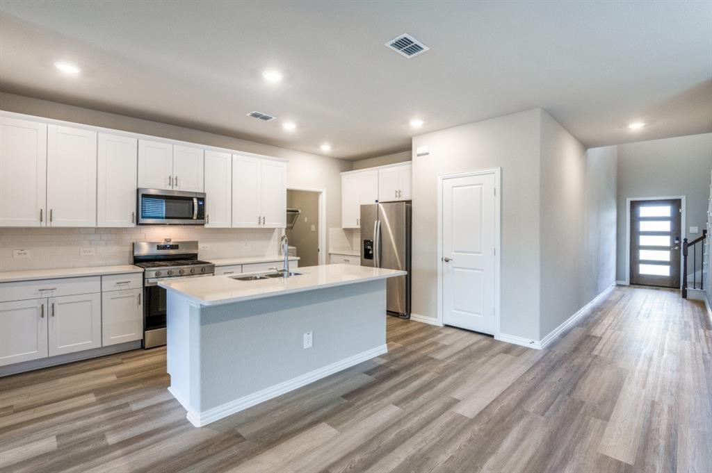 Kitchen featuring white cabinetry, center island with stone-finish countertop, stainless steel appliances, wood-finish flooring, and recessed lighting