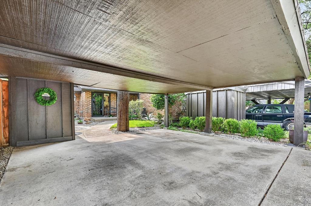 Covered carport featuring a concrete parking surface, wood-paneled ceiling, and structural wood supports