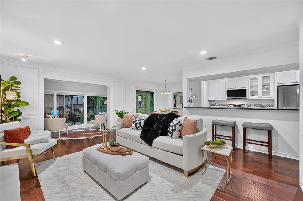 Open-concept living space featuring wood-finish flooring, recessed lighting, wainscoting, and a kitchen pass-through with a breakfast bar Open-concept living space featuring wood-finish flooring, recessed lighting, wainscoting, and a kitchen pass-through with a breakfast bar