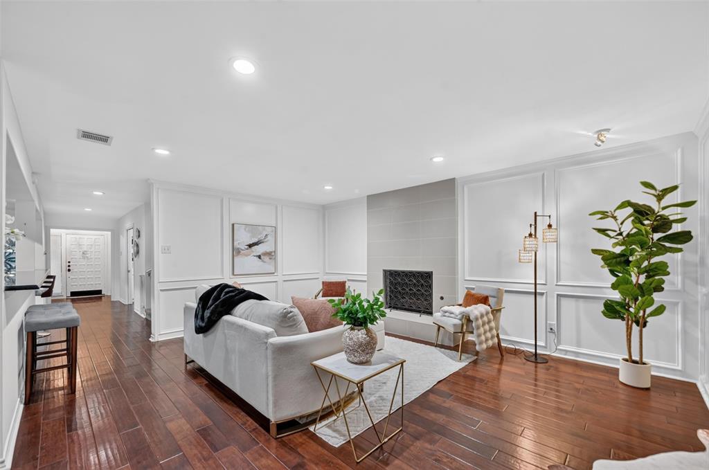 Wood-finish flooring, fireplace with neutral tile surround, and extensive wall molding Wood-finish flooring, fireplace with neutral tile surround, and extensive wall molding