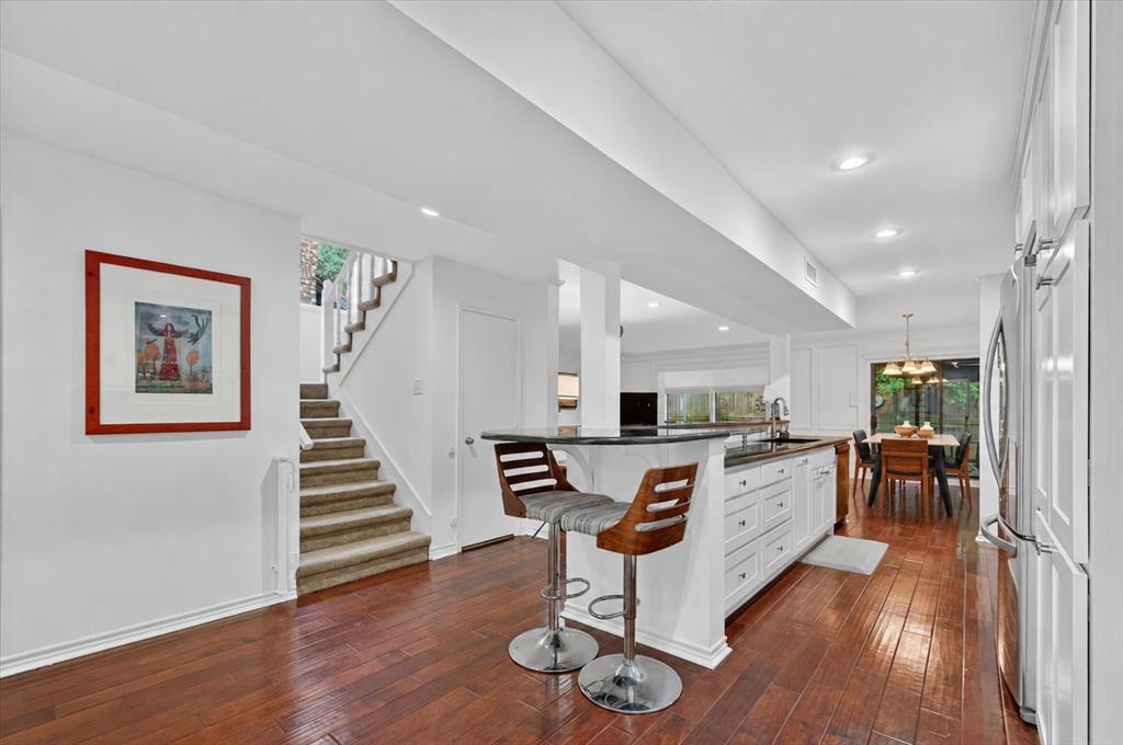 Kitchen featuring white shaker-style cabinetry, dark stone countertops, recessed lighting, and wood-finish flooring