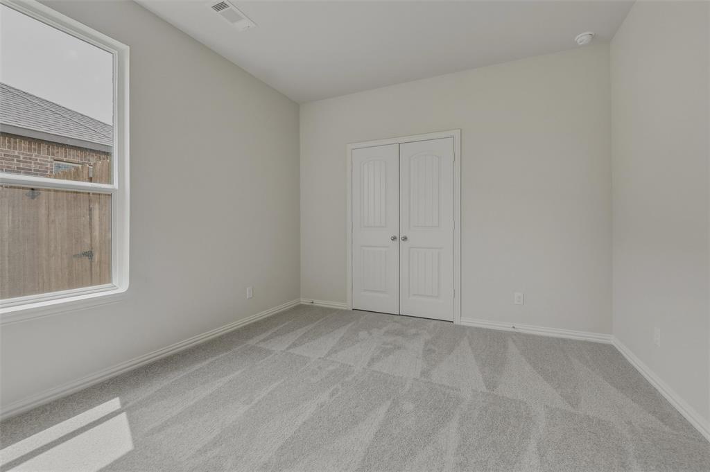 Bright secondary bedroom showcasing plank-style wood-finish flooring, abundant natural light from a large window, and dual closets with white panel doors for ample storage
