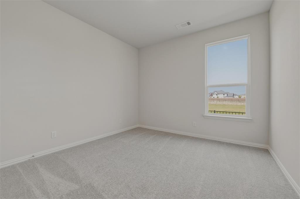 Neutral wall paint, light-colored carpeting, and a large window providing natural illumination