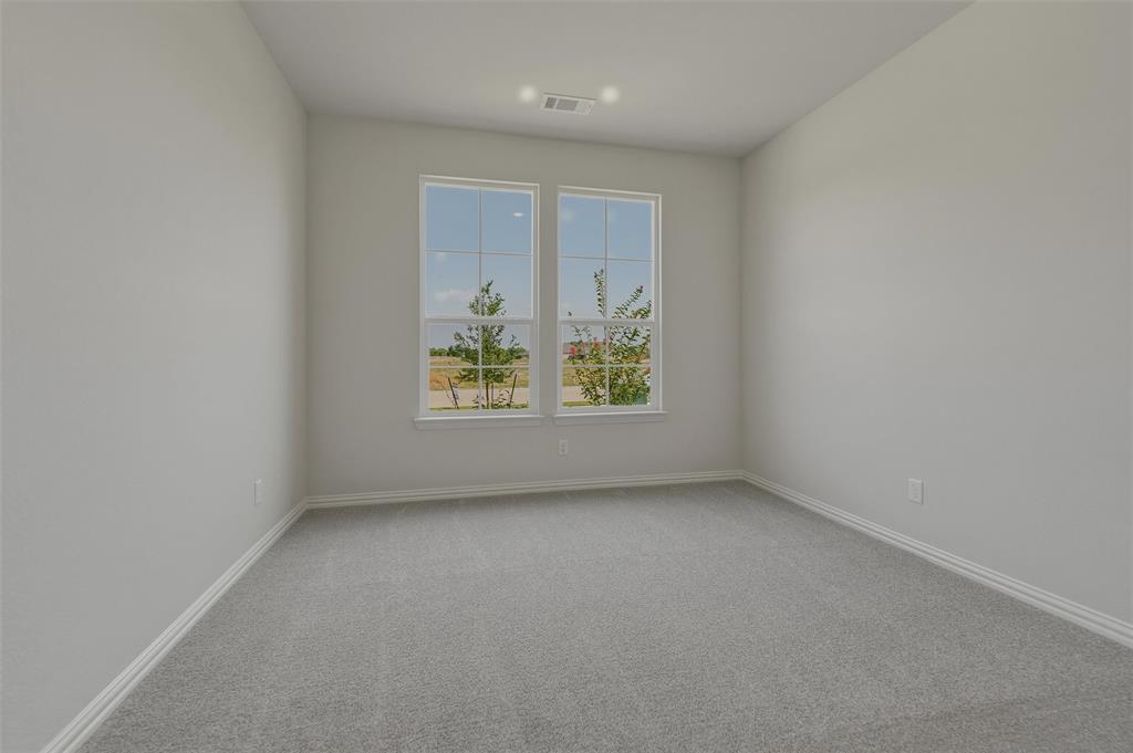 Bright, light-filled bedroom featuring dual casement windows with expansive natural light, neutral wall finishes, and soft gray carpet flooring