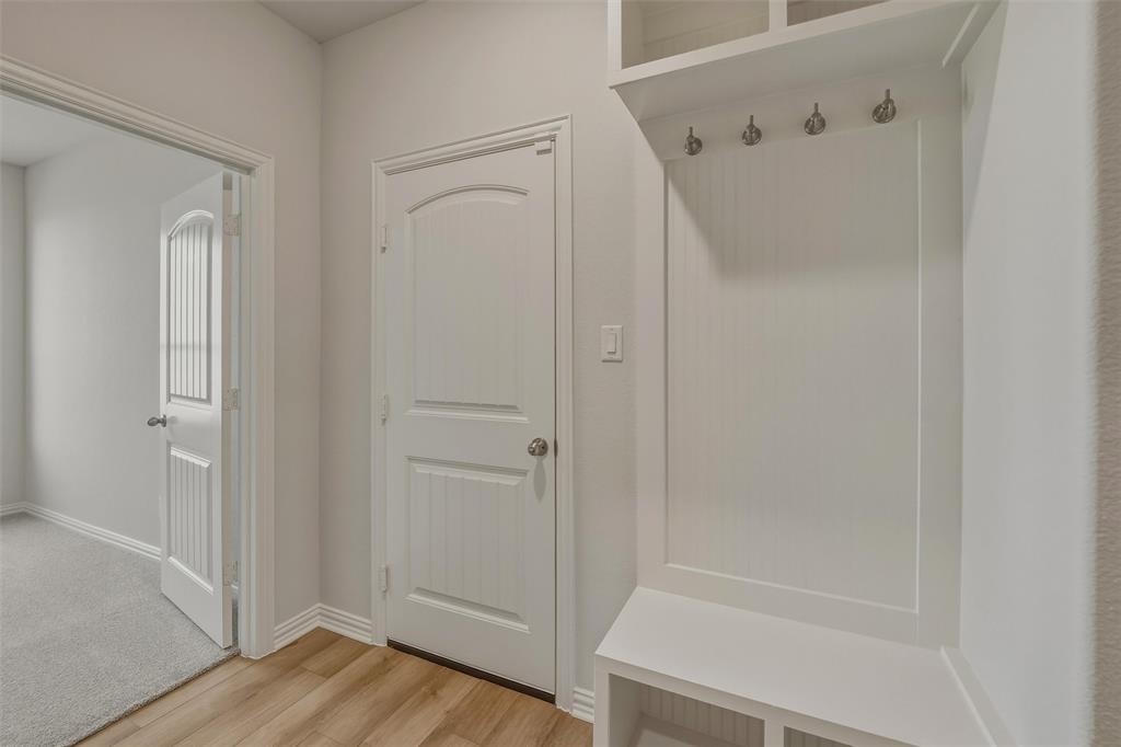 Built-in coat rack with storage cubbies, wood-finish flooring, and white paneled doors