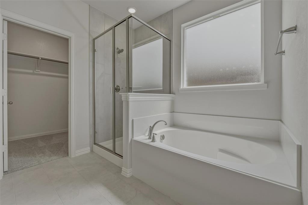 Built-in soaking tub, glass-enclosed shower, tiled shower surround, recessed lighting, and frosted window
