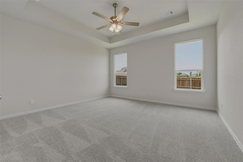 Spacious room featuring a tray ceiling, ceiling fan, two large windows, and wall-to-wall carpeting