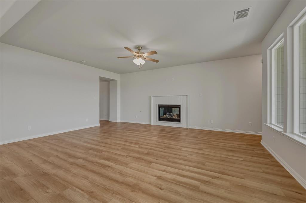 Wood-finish flooring throughout, multiple windows, and a built-in fireplace with a mantel