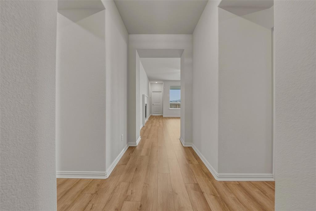 Hallway featuring wood-finish flooring, light-toned walls, and white trim