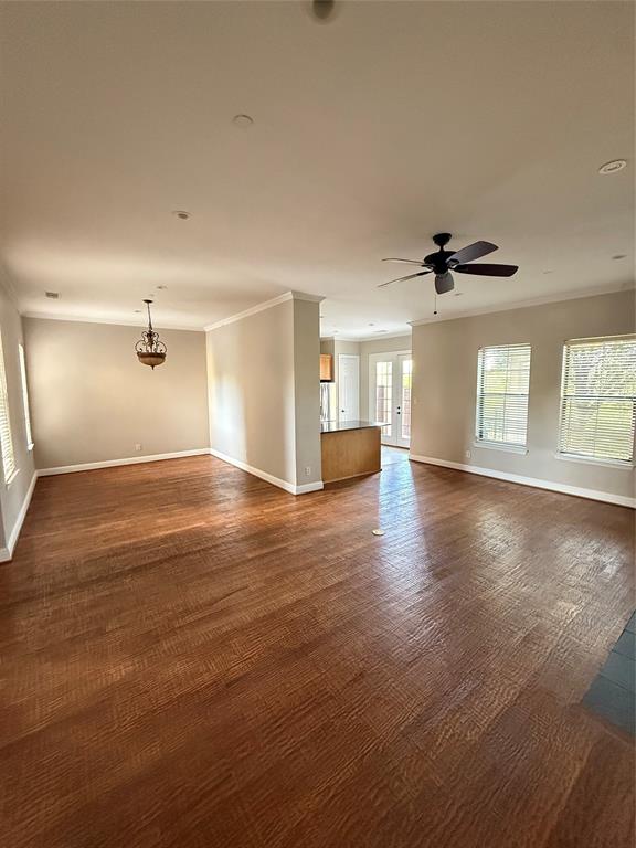Open interior featuring wood-finish flooring, crown molding, recessed lighting, a ceiling fan, and multi-paned glass exterior doors Open interior featuring wood-finish flooring, crown molding, recessed lighting, a ceiling fan, and multi-paned glass exterior doors