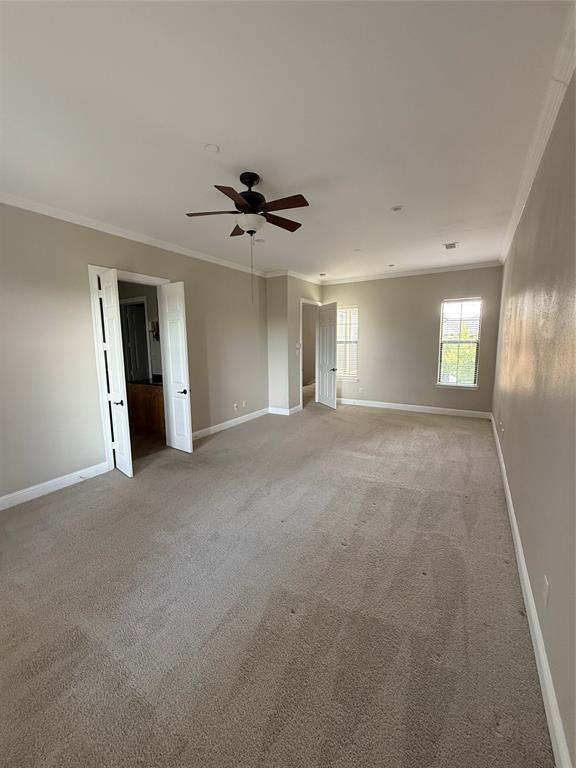 Room featuring neutral wall tones, crown molding, wall-to-wall carpeting, a ceiling fan with integrated lighting, and French doors