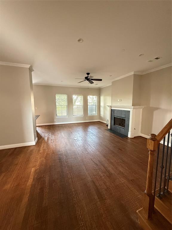 Living area featuring wood-finish flooring, fireplace with dark tile surround, triple-pane windows, and ceiling fan Living area featuring wood-finish flooring, fireplace with dark tile surround, triple-pane windows, and ceiling fan
