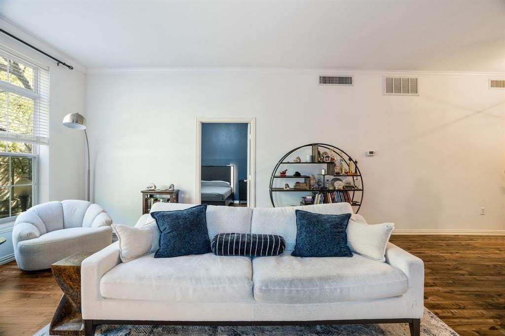 Expansive living area featuring tall windows, wood-finish flooring, and crown molding