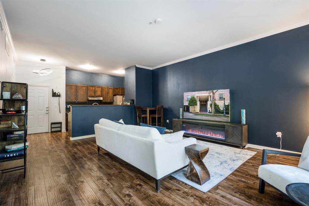 Open-concept interior featuring wood-finish flooring, dark-toned accent wall, crown molding, and recessed lighting
