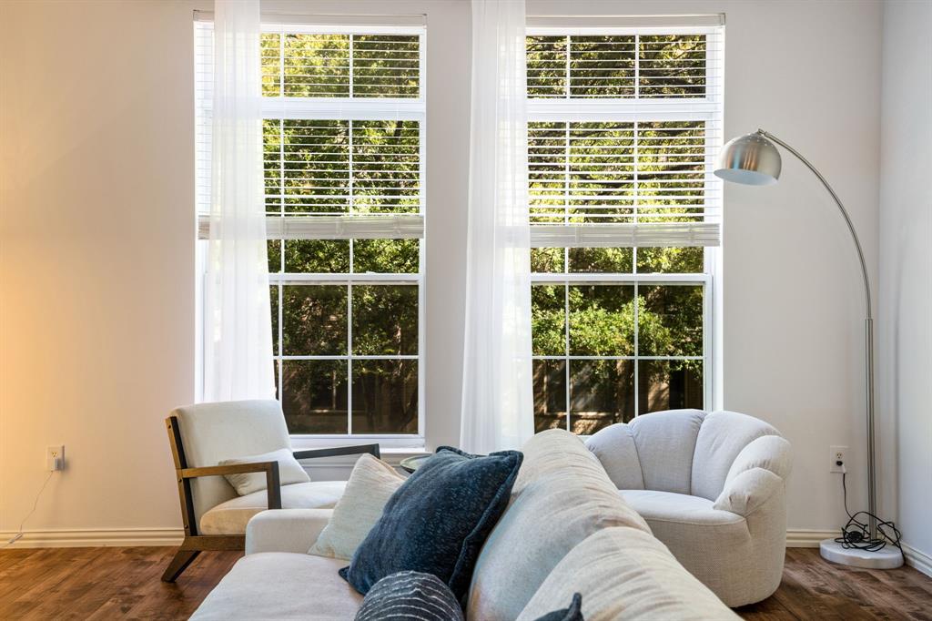 Dual floor-to-ceiling windows with mullion detailing, horizontal blinds, and wood-finish flooring