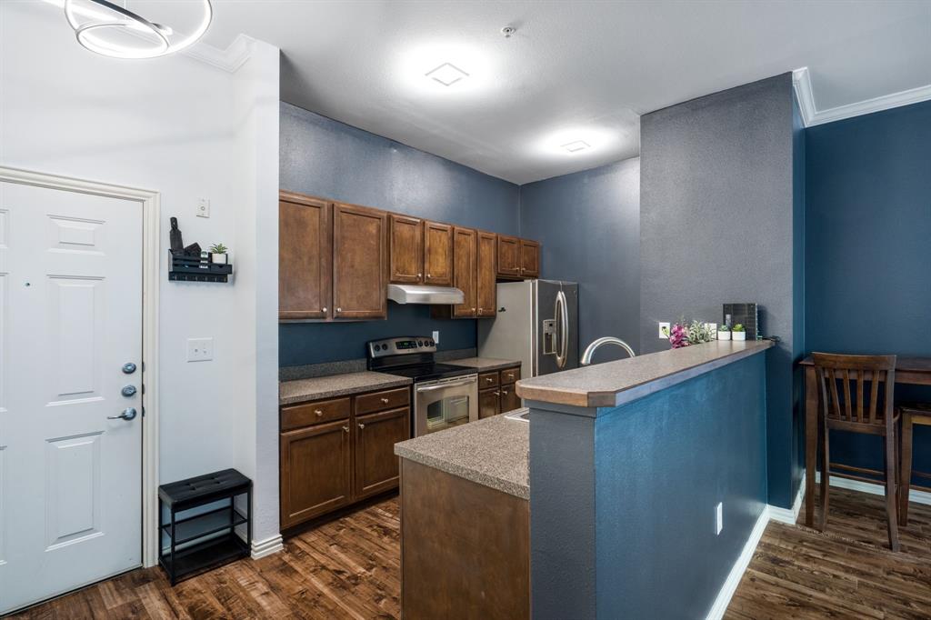 Kitchen featuring wood cabinetry, stone-finish countertops, stainless steel appliances, and wood-finish flooring