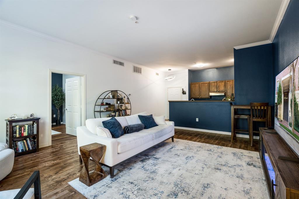 Living area featuring wood-finish flooring, crown molding, and a dark-toned accent wall