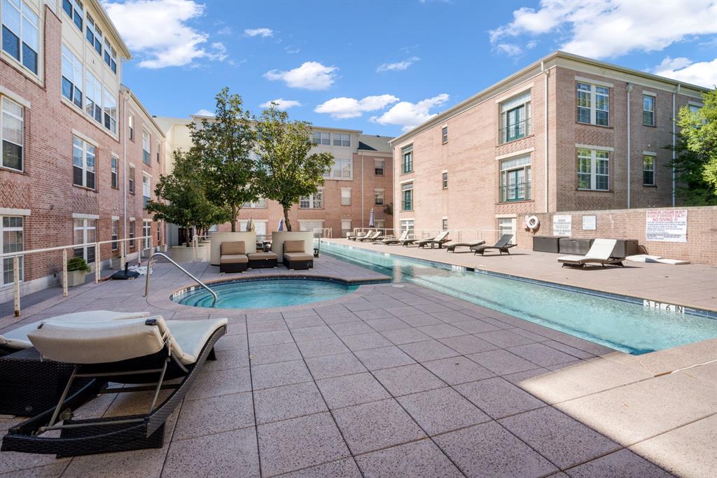 Swimming pool and attached spa area with paved deck, surrounded by brick building exteriors