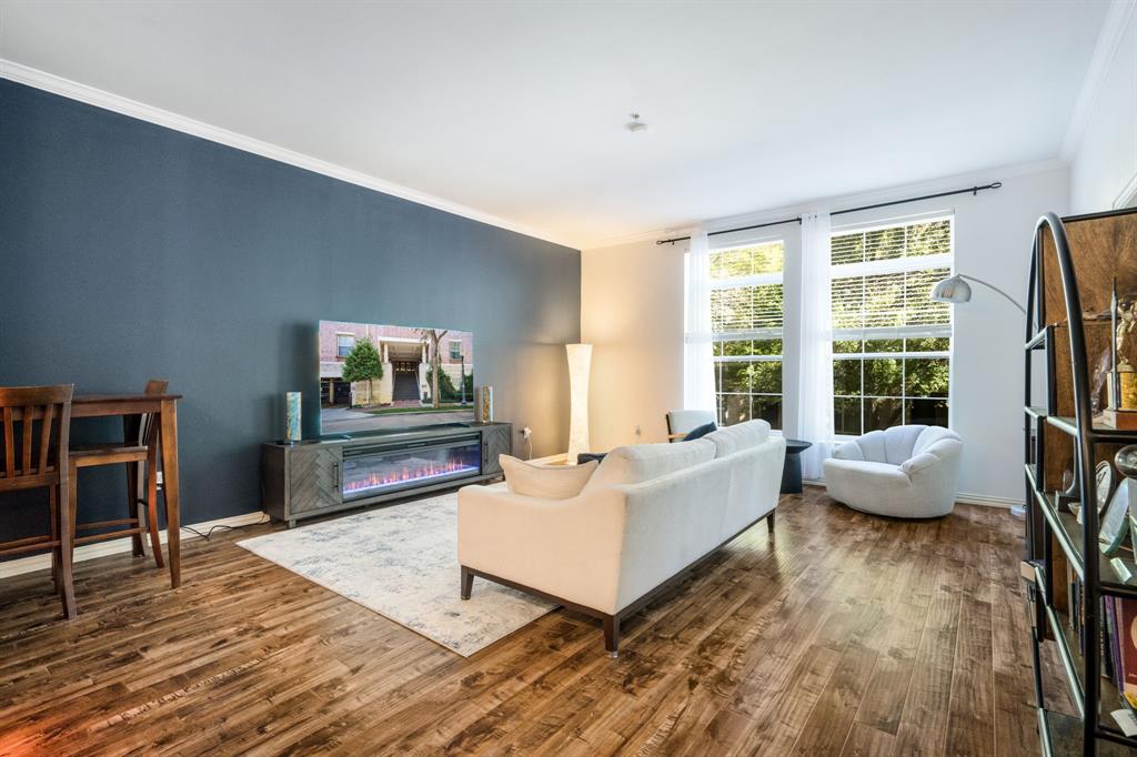 Living space featuring wood-finish flooring, dual tall windows, and a prominent blue accent wall
