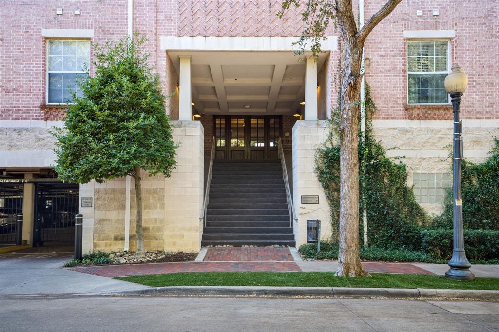 Exterior facade featuring patterned brickwork, stone masonry, a recessed entry with coffered ceilings, multi-pane glass doors, and a grand staircase with metal handrails