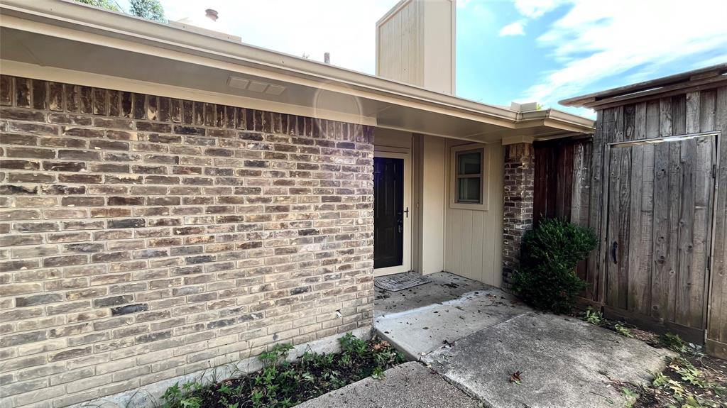 Exterior featuring a multi-toned brick facade, vertical wood-panel siding, a covered entryway, and a solid-panel front door