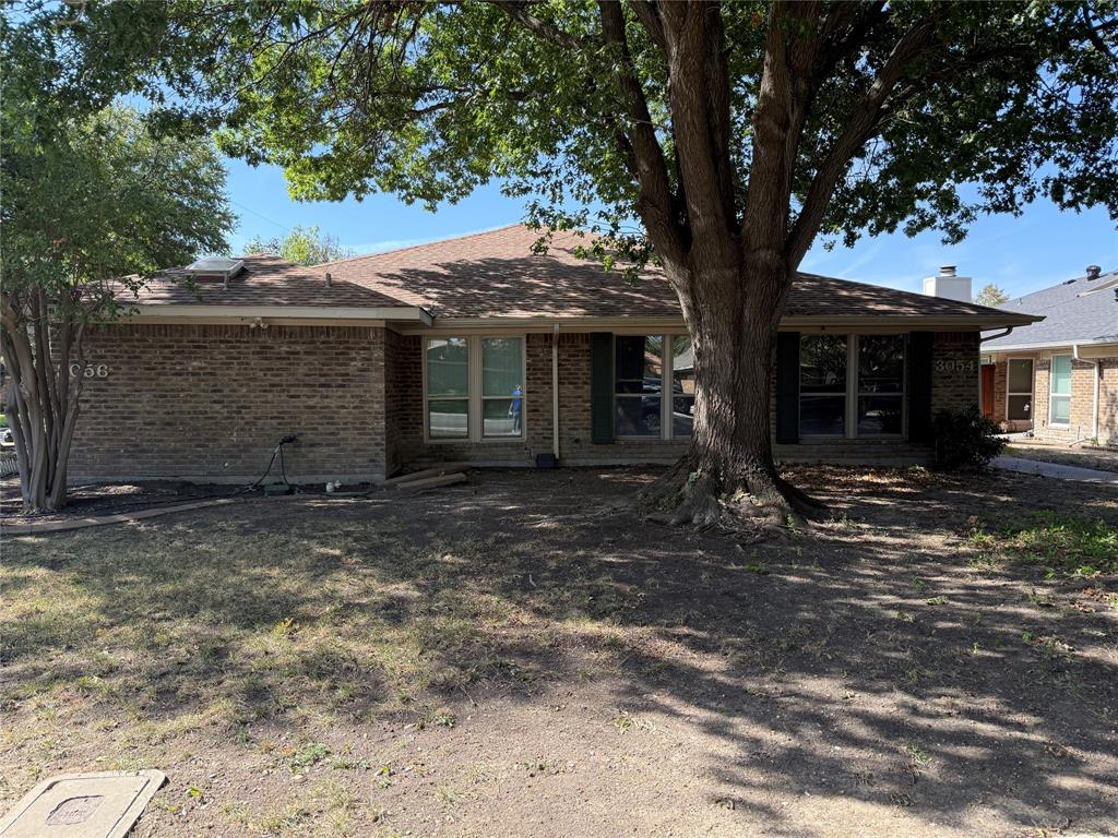 Single-story brick exterior featuring a hip roof, multi-pane windows, and mature trees Single-story brick exterior featuring a hip roof, multi-pane windows, and mature trees