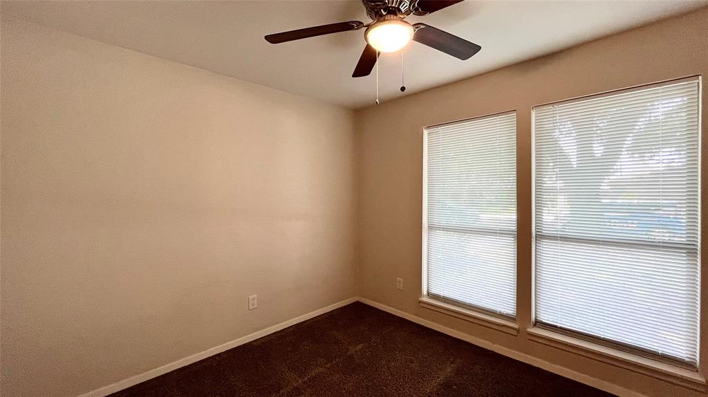Interior space featuring neutral wall paint, carpeting, dual windows, and a ceiling fan with integrated lighting