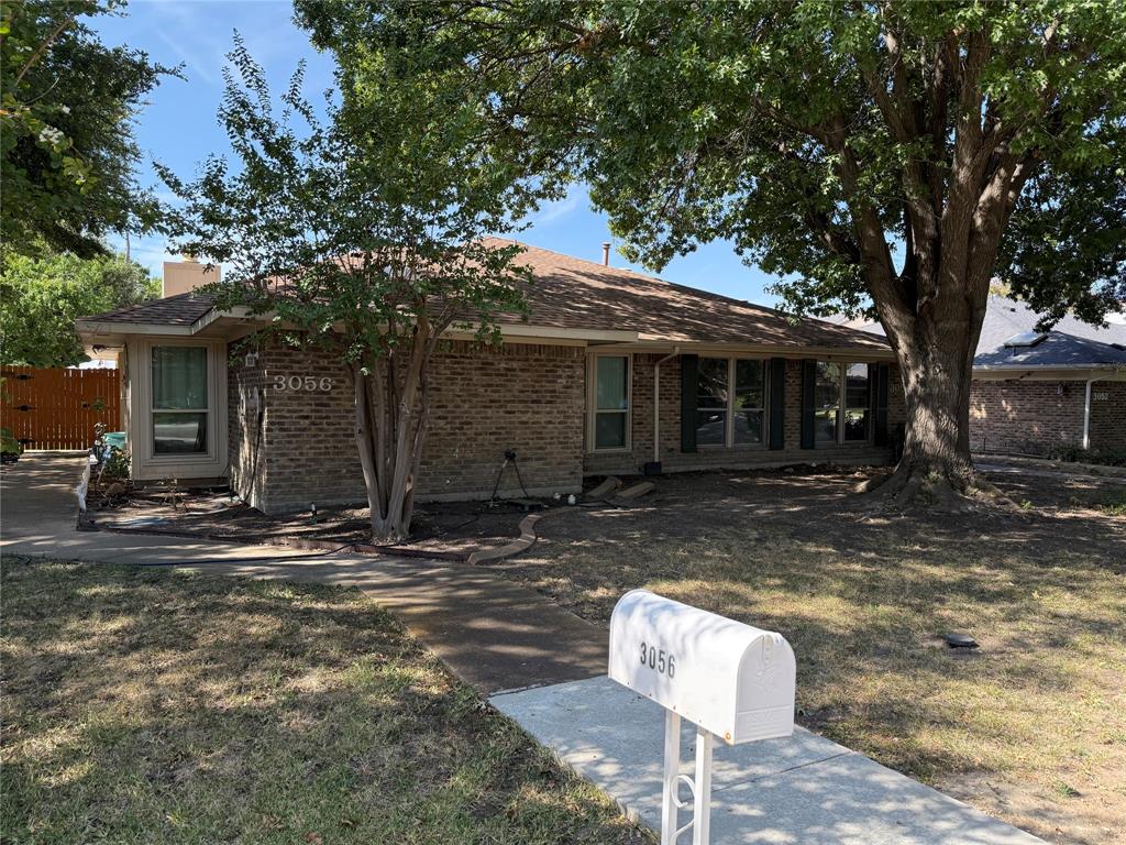 Single-story brick exterior featuring a hip roof, multi-pane windows, and mature trees on the property Single-story brick exterior featuring a hip roof, multi-pane windows, and mature trees on the property