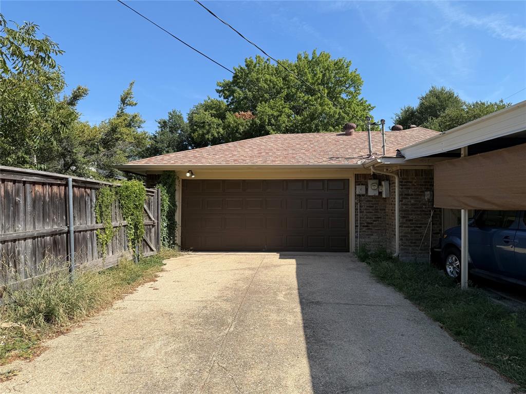 Detached two-car garage with sectional door, masonry exterior, asphalt shingle roof, and attached carport Detached two-car garage with sectional door, masonry exterior, asphalt shingle roof, and attached carport
