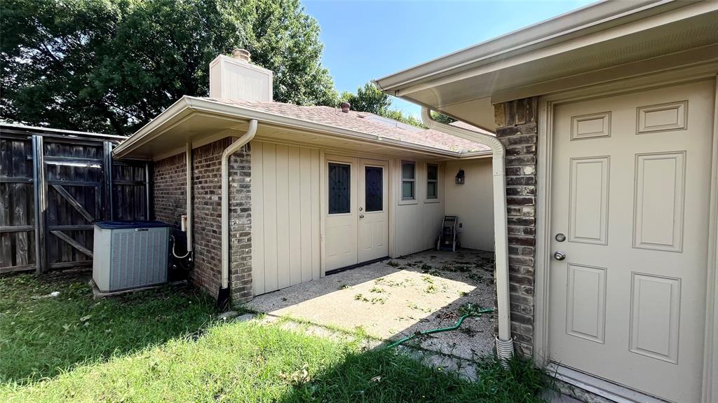 Exposed aggregate concrete patio featuring brick and vertical siding exterior, dual-pane entry doors, and multi-panel solid core door