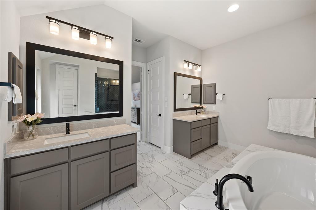 Dual vanities featuring quartz countertops, undermount sinks, matte black fixtures, and custom cabinetry with framed mirrors