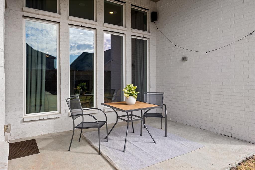 Covered patio featuring white painted brick masonry, concrete flooring, and multiple floor-to-ceiling windows with transoms