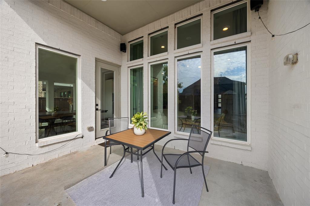 Covered patio featuring a painted brick exterior, concrete flooring, and multiple floor-to-ceiling windows with transoms