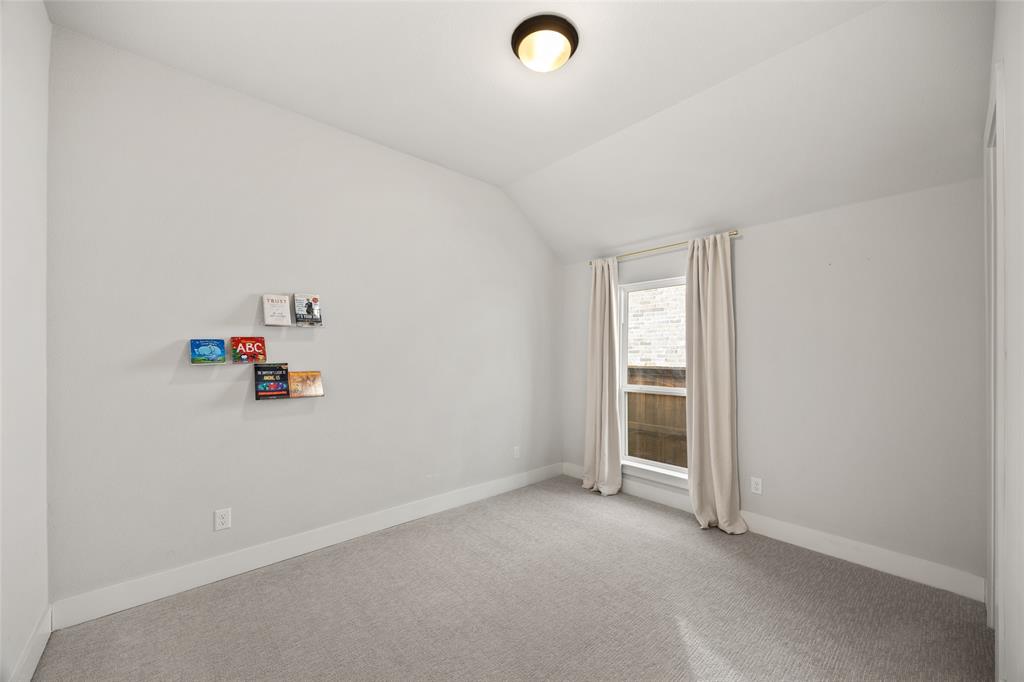 Neutral-toned room featuring vaulted ceilings, neutral carpeting, and a flush-mount ceiling light fixture