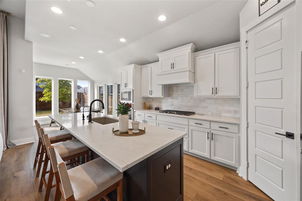 Kitchen featuring white cabinetry, stone countertops, a dark-toned center island, recessed lighting, and wood-finish flooring Kitchen featuring white cabinetry, stone countertops, a dark-toned center island, recessed lighting, and wood-finish flooring