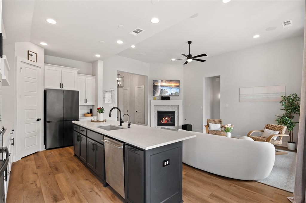 Kitchen featuring a two-tone island with a light-colored countertop, recessed lighting, wood-finish flooring, and a fireplace with a decorative surround