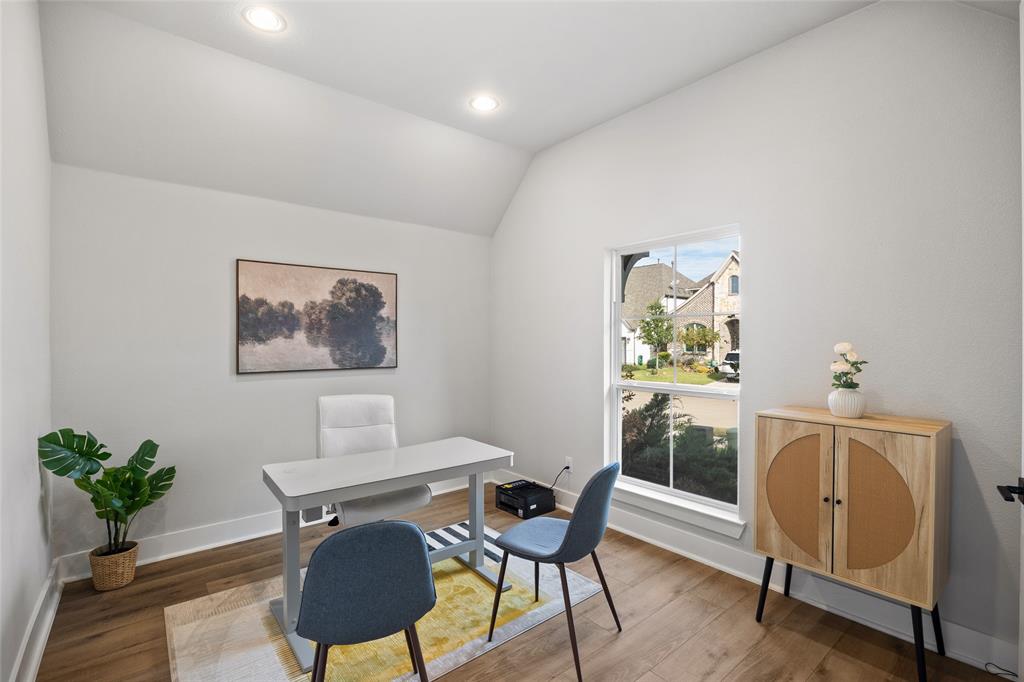 Vaulted ceilings, wood-finish flooring, and natural light through a large window