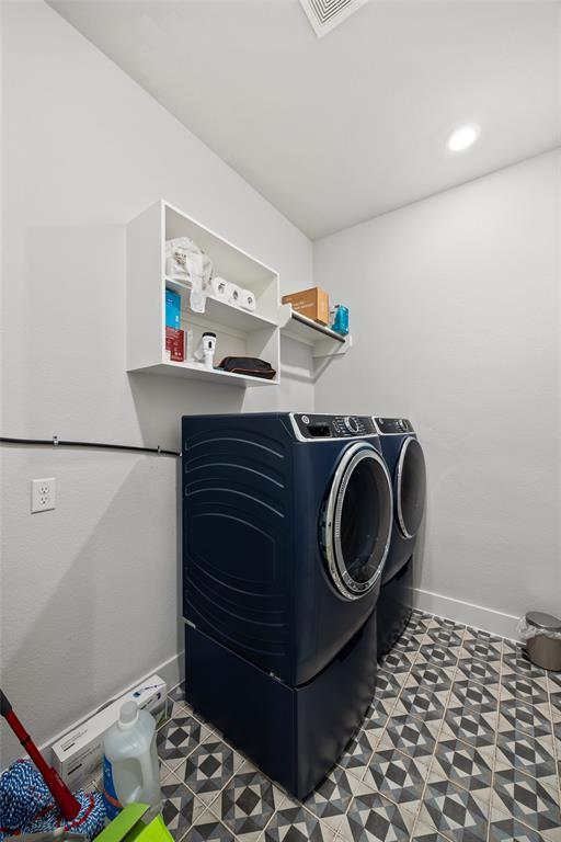 Utility space featuring patterned tile flooring and wall-mounted white cabinetry