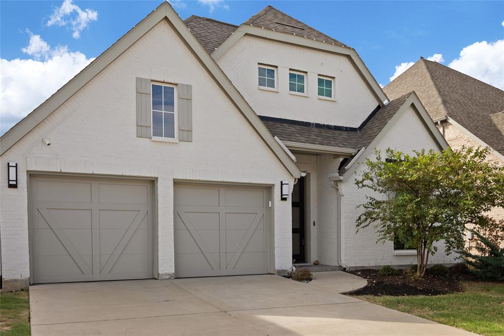 Painted brick exterior with a multi-gabled roofline, two-car garage with carriage-style doors, and decorative exterior shutters