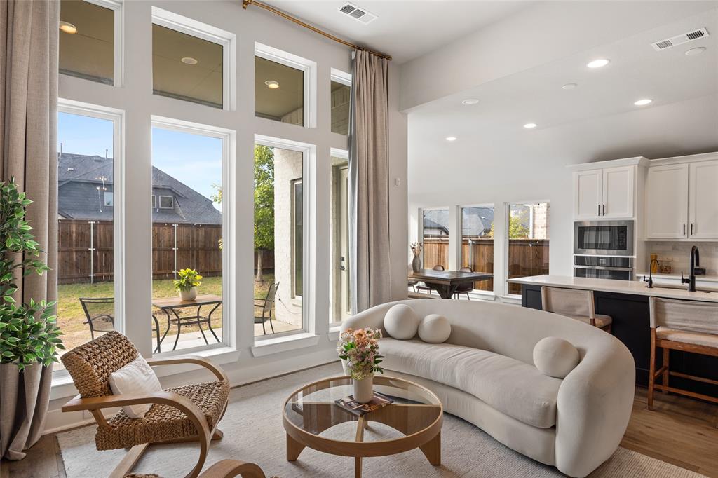 Expansive windows with transom accents, recessed lighting, white cabinetry with contrasting kitchen island, wood-finish flooring, and built-in wall oven and microwave combination