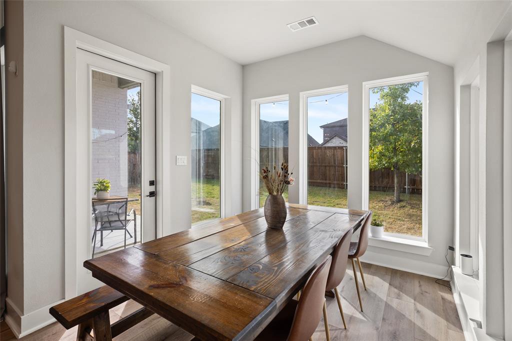 Sunroom featuring high vaulted ceilings, expansive floor-to-ceiling windows, wood-finish flooring, and a glass-paneled exterior door