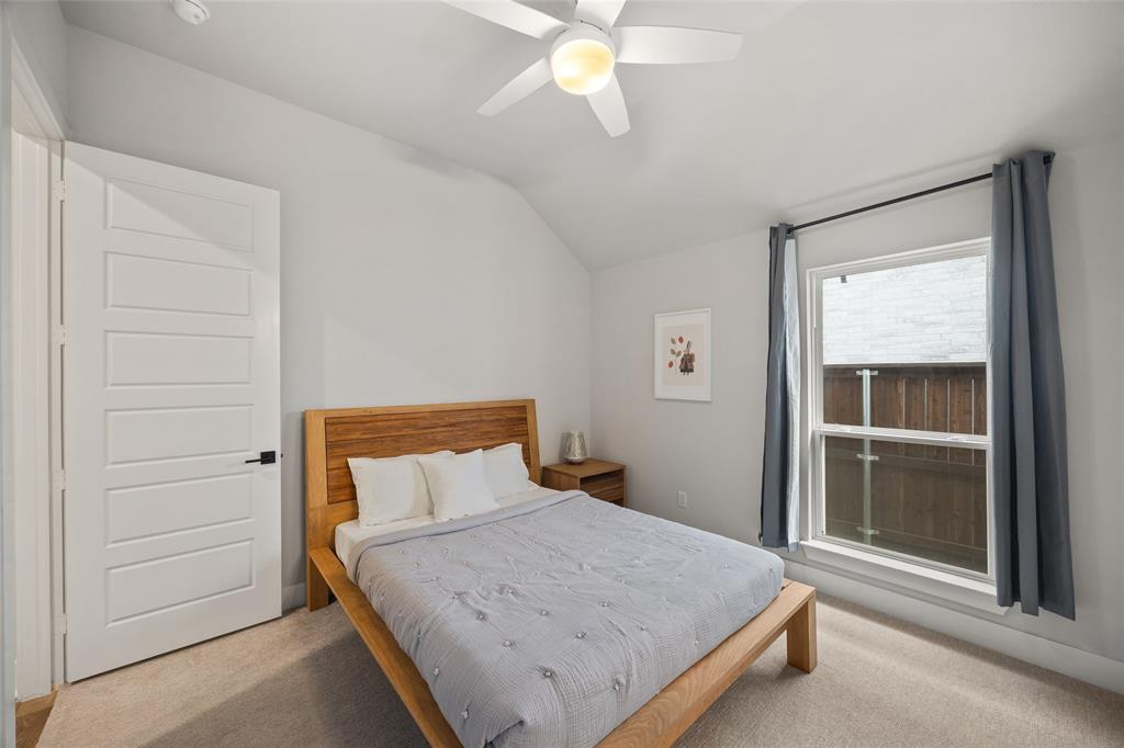 Vaulted ceilings, neutral carpeting, five-panel interior door, and a ceiling-mounted light fixture with fan