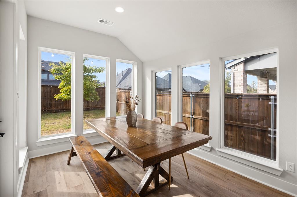 Sunroom featuring a vaulted ceiling, wood-finish flooring, and five expansive windows