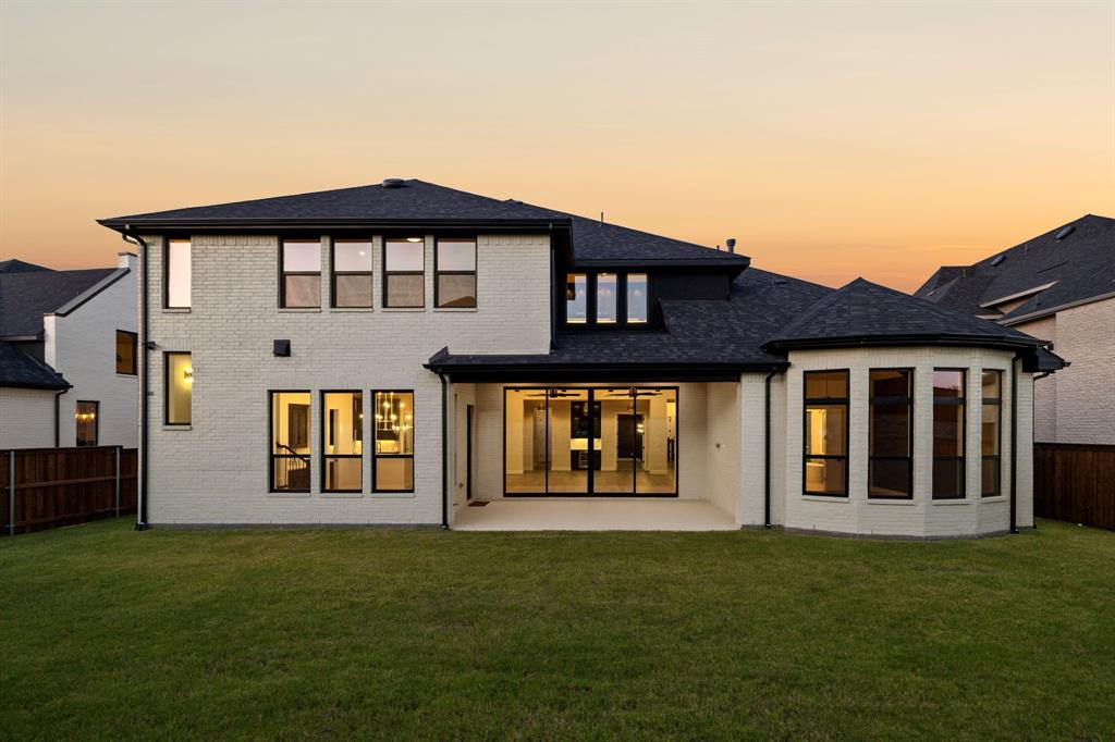 Exterior facade featuring white brick masonry, black window framing, architectural shingle roofing, a covered concrete patio, and a turret-style bay window