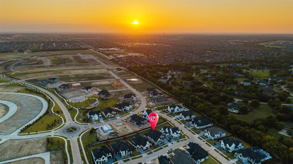 Aerial perspective of a residential lot featuring paved street access, established curbs, and a clear horizon line