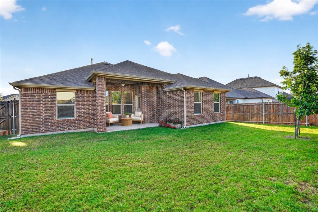 Brick exterior, covered rear patio, multi-pane windows, and wood-style privacy fencing