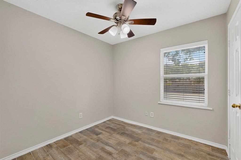 A cozy second bedroom featuring a ceiling fan and a window letting in natural light.