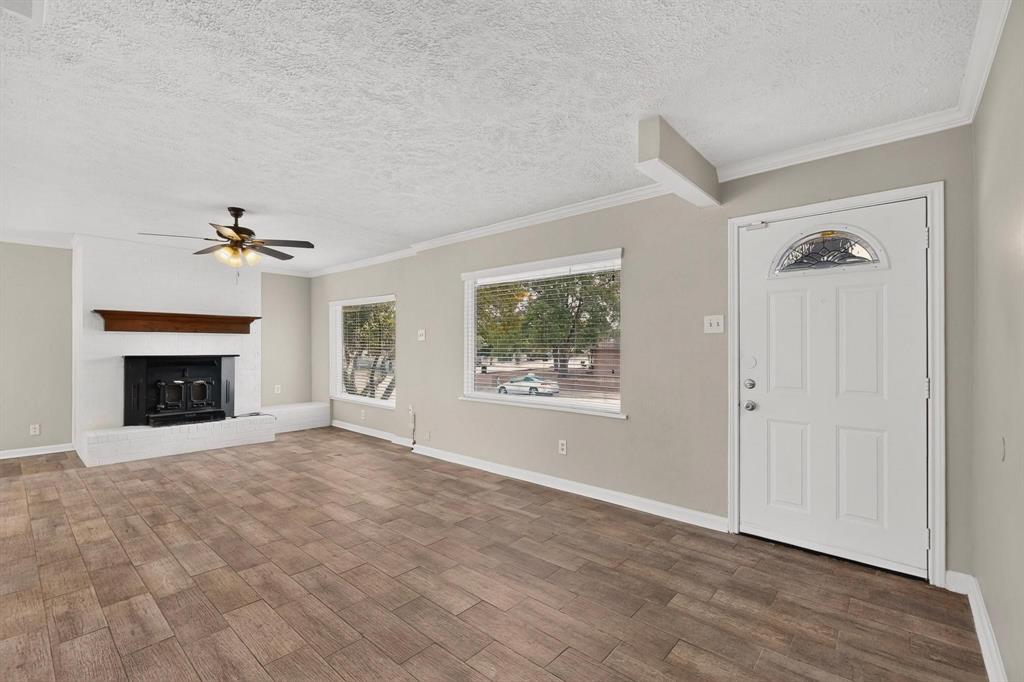 A spacious living room featuring hardwood floors, a fireplace, a ceiling fan and wide windows, perfect for relaxation and gatherings. A spacious living room featuring hardwood floors, a fireplace, a ceiling fan and wide windows, perfect for relaxation and gatherings.