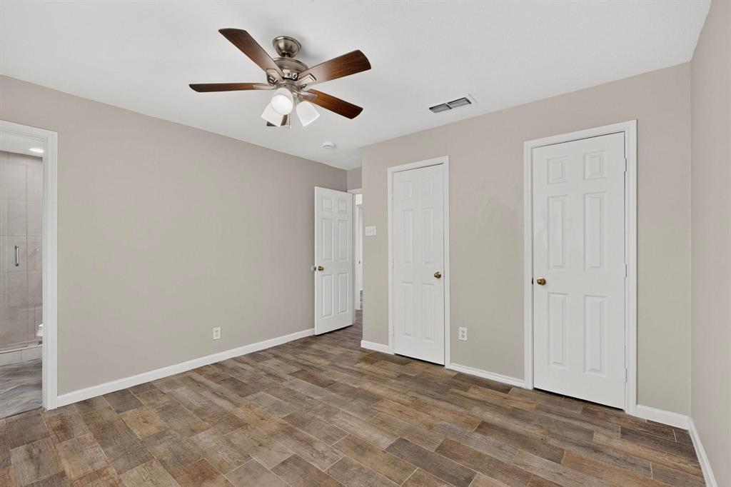 Bright primary bedroom with a ceiling fan, hardwood floors, two separate closets and an en suite bath, perfect for relaxation.